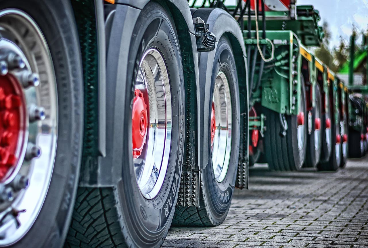 Close-up of large truck wheels lined up on a paved surface.