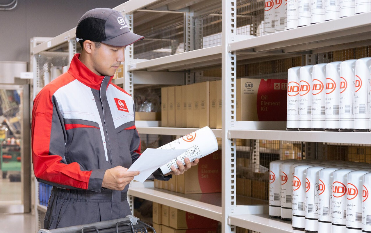 Worker in uniform checks inventory on shelves stocked with cans in a warehouse.