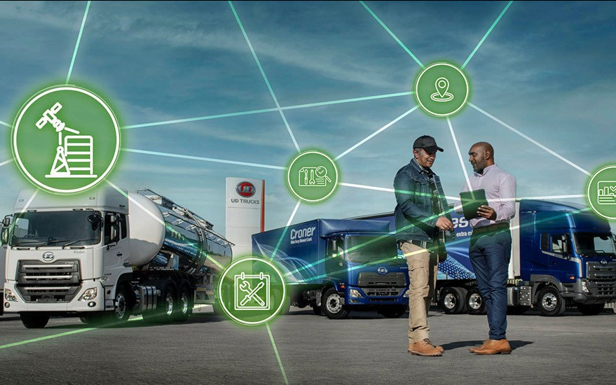 Two men shake hands near trucks with digital network icons overlayed.