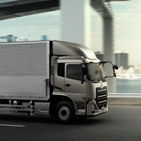 Silver truck driving on a city motorway with blurred buildings in the background.