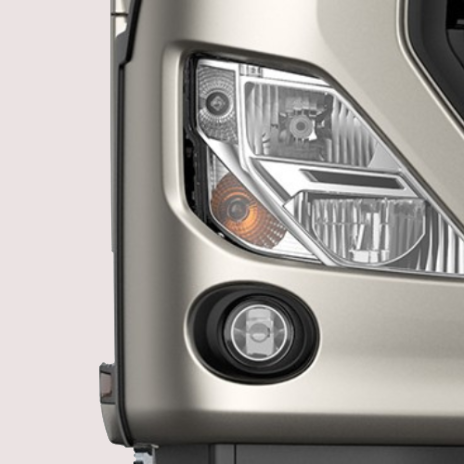 Close-up of a silver truck headlight and round fog light.