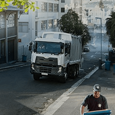 Basurero sa kalsada at lalaking nagtutulak ng asul na garbage bin