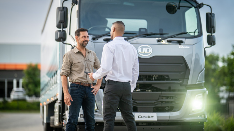 トラックの前で握手する二人の男性