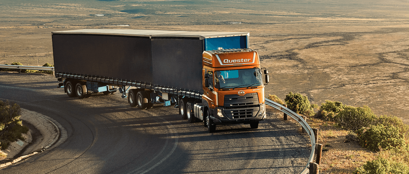 Xe tải màu cam đang chạy trên đường cong giữa vùng hoang mạc.